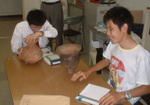 歴史の授業で弥生土器を触っている生徒