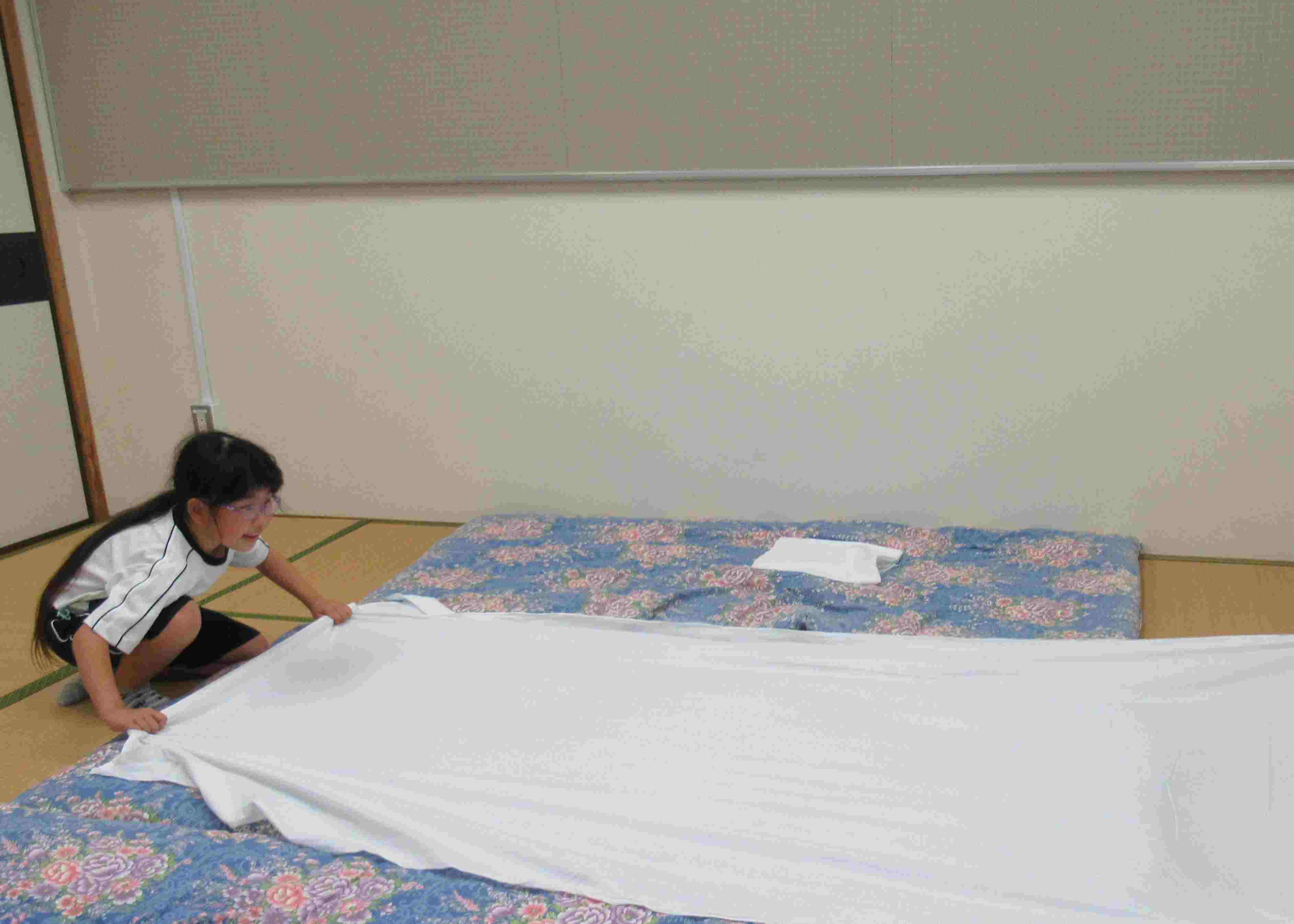 画像：敷き布団にシーツをかけている児童の写真